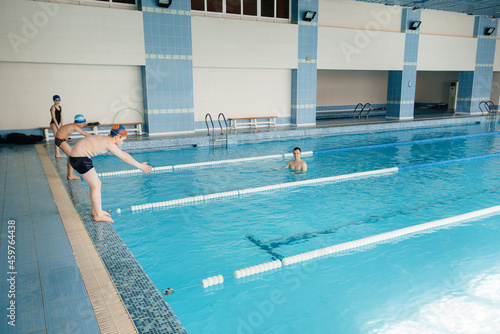 A group of boys and girls train and learn to swim in the pool with an instructor. Development of children's sports.