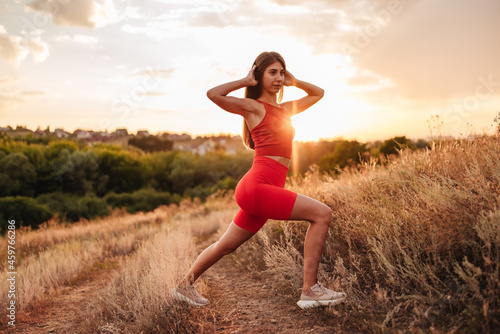 Fitness woman ready for running at sunset or sunrise on beach. Female athlete in powerful starting line pose.