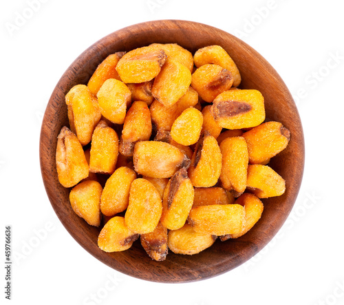 Roasted salted corn nuts in wooden bowl, isolated on white background. Beer snack, dry corn with spices. Top view.