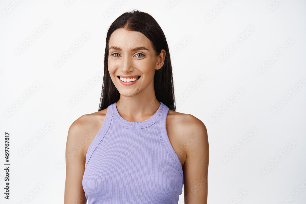 Portrait of beautiful woman with long dark hair, natural makeup, smiling at camera, standing against white background Portrait of beautiful woman with long dark hair, natural makeup, smiling at camera, standing against white background