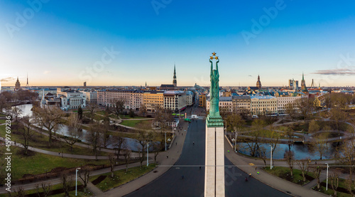 Amazing Aerial panoramic view to Monument of freedom with old town in background  during autumn sunrise. Milda - Statue of liberty holding three Golden stars over the city. Riga  Latvia  Europe.