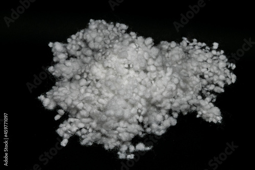 Synthetic fiber, polyester fiber, white synthetic winterizer on a black background, siliconized holofiber. It is used as a filler for blankets, pillows, clothes and upholstered furniture.