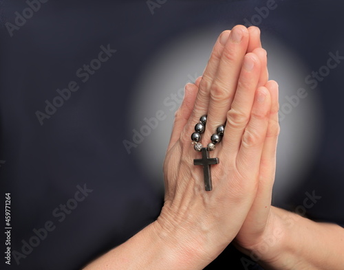 hands praying together on black background stock photo