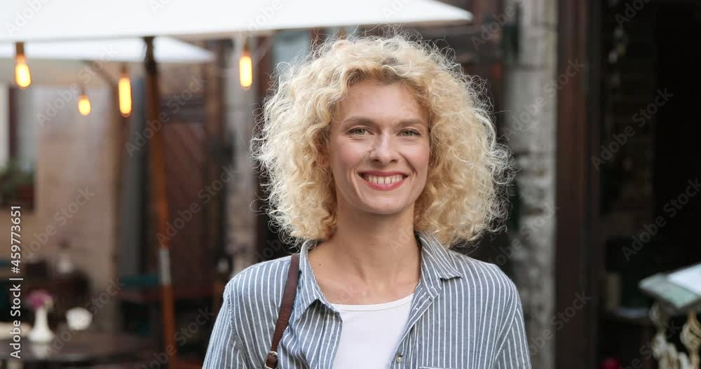 Close up of face of caucasian woman with blonde hair. Portrait of attractive female looking at side ad then turning face to camera with smile at street in town. Outdoors Close up of face of caucasian woman with blonde hair. Portrait of attractive female looking at side ad then turning face to camera with smile at street in town. Outdoors