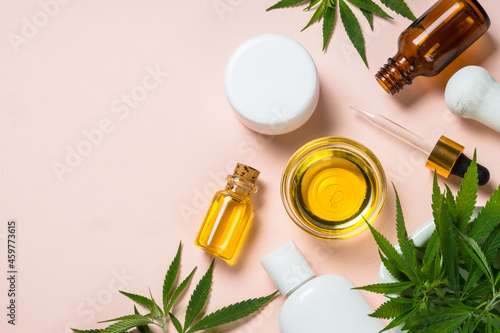Cannabis cosmetic products. Cannabis oil, cream, soap and fresh leaves at pastel background. Flat lay with copy space.