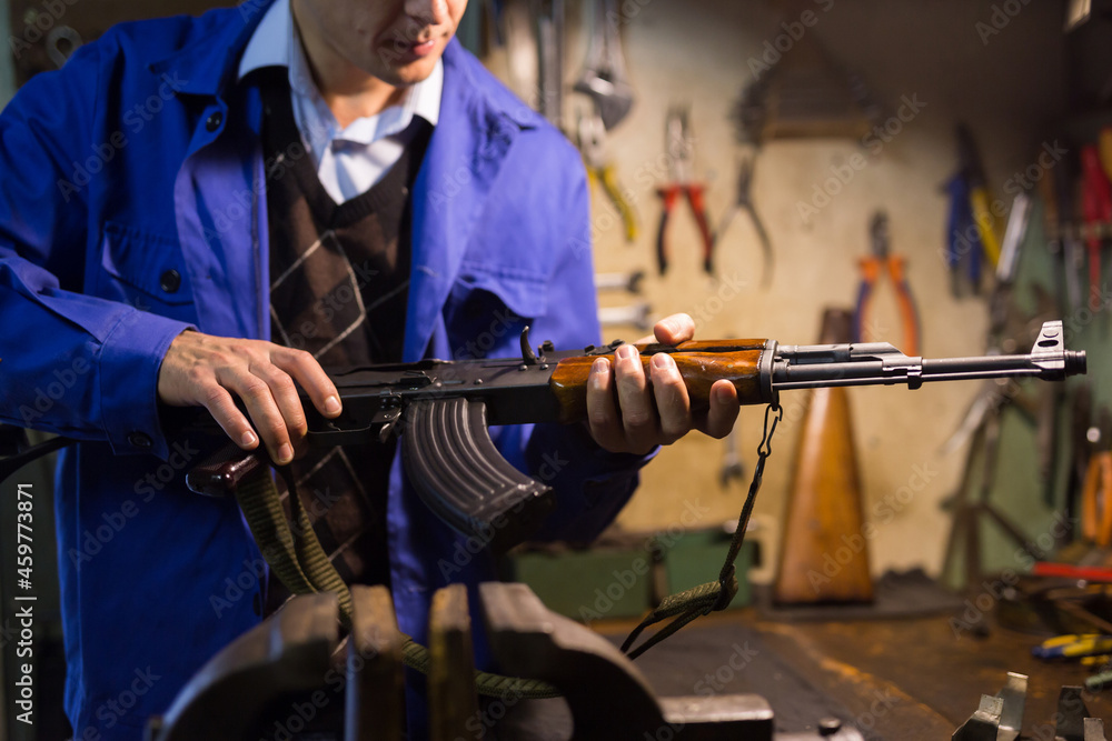 Closeup of Kalashnikov assault rifle in hands of gunsmith. Professional firearms maintenance concept