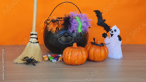 Happy Halloween concept. Decoration with halloween accessories on the table, with orange background. photo
