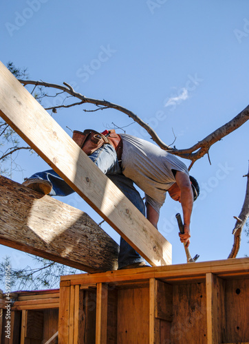 Картината върху платно Carpenter nailing a new roof joist into place