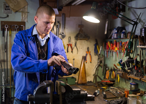 Portrait of qualified confident master of weapons working in workshop, repairing or renovating firearms . © JackF
