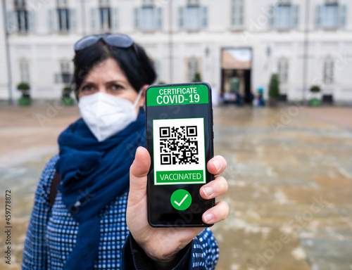 Young woman holding smartphone with qr code confirm vaccination coronavirus covid-19. Vaccine done with digital green pass passport photo