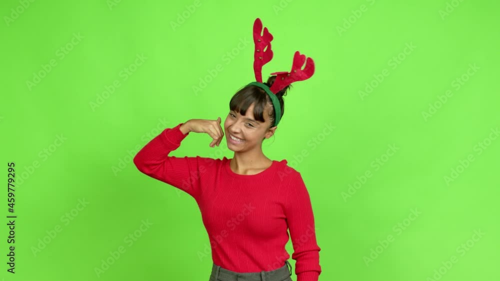 Young woman wearing christmas hat making phone gesture and speaking with someone. Call me back sign over isolated background. Green screen chroma key Young woman wearing christmas hat making phone gesture and speaking with someone. Call me back sign over isolated background. Green screen chroma key