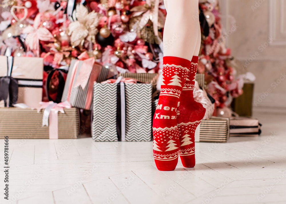 Ballerina's feet in pointe shoes with Christmas and New Year socks around  decor and gifts Stock Photo