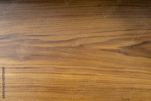 The teak wood background is coated with a matt lacquer showing the wood grain.