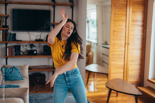 Woman dancing while wearing headphones and listening music at home