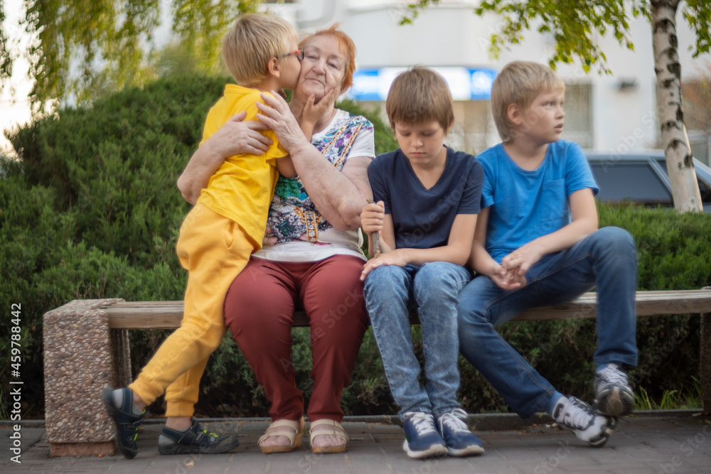 elderly woman sits on park bench with her beloved grandchildren