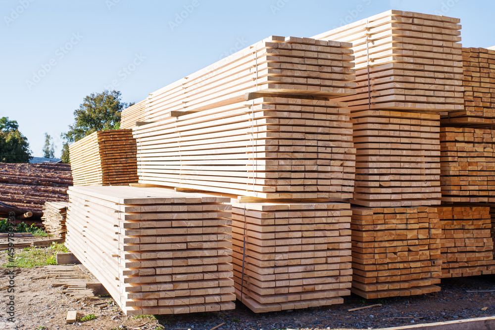 Stacked stacks of wooden planks against the sky. Lumber warehouse, wood drying. Lumber for construction. Stacked stacks of wooden planks against the sky. Lumber warehouse, wood drying. Lumber for construction.