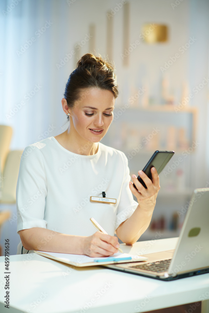 smiling female worker with clipboard in modern beauty salon smiling female worker with clipboard in modern beauty salon