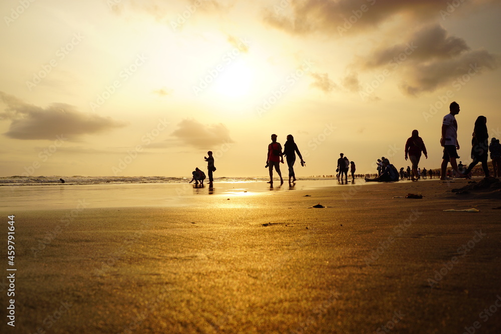 Selective low angle shot of silhouettes of beachgoers enjoying the sunset at Parangtritis beach, Yogyakarta Selective low angle shot of silhouettes of beachgoers enjoying the sunset at Parangtritis beach, Yogyakarta