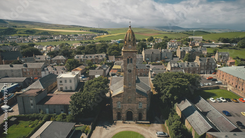 Closeup ancient church at Europe town aerial. Historical architecture attraction at Scotland. Campbeltown city streets with old buildings. European cityscape: historic tourist landmark. Road with cars