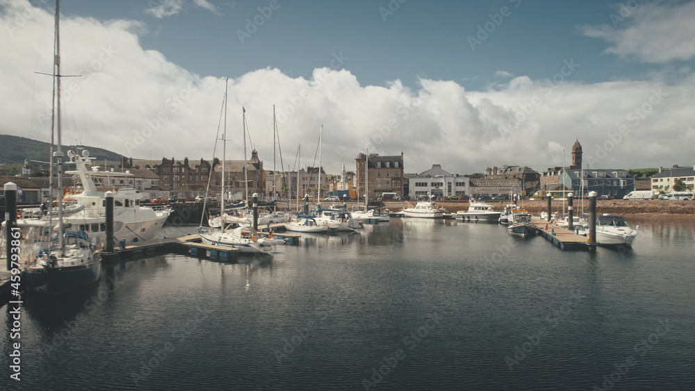Ships, yachts at ocean bay aerial. Cityscape with modern and historic architecture landmark at port city of Campbeltown, Scotland, Europe. Downtown streets: old buildings at traffic highway