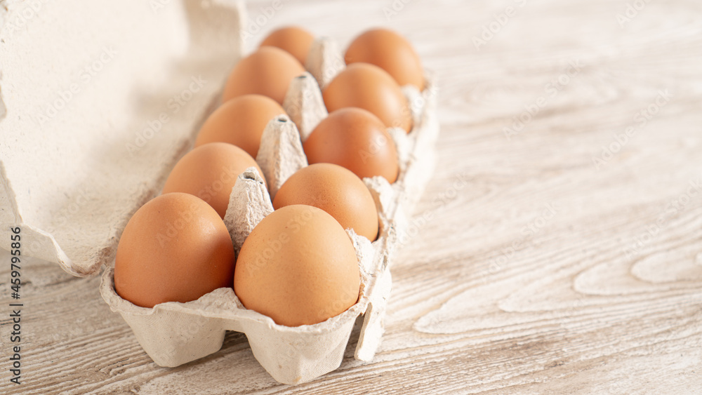 Brown fresh eggs in a paper container on wooden table. Farm eggs in carton box with copy space. Brown fresh eggs in a paper container on wooden table. Farm eggs in carton box with copy space.
