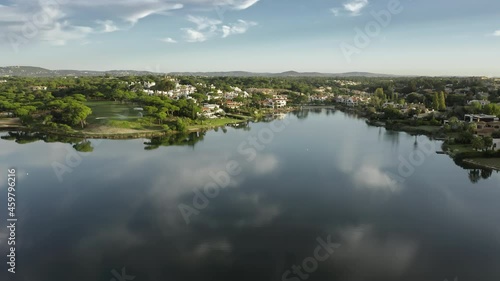 Aerial view of water surface of Quinta do Lago with houses on coastline, Algarve, Portugal, Europe. Modern cottages in green landmark located at lake. Lakeside villas in city, 4k footage