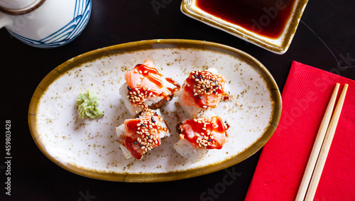 Traditional Japanese food appetizer - uramakizushi rolls with filling of raw salmon and avocado seasoned with unagi sauce and sesame seeds, served with with spicy wasabi and soy sauce photo