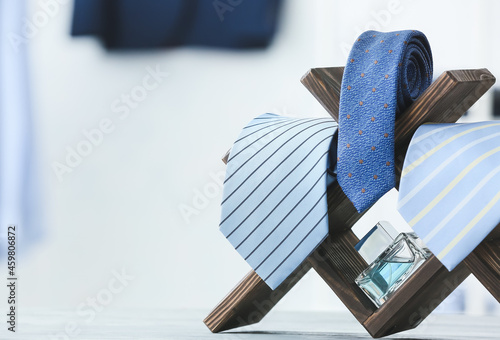 Fotografia Stand with stylish neckties and perfume on table, closeup