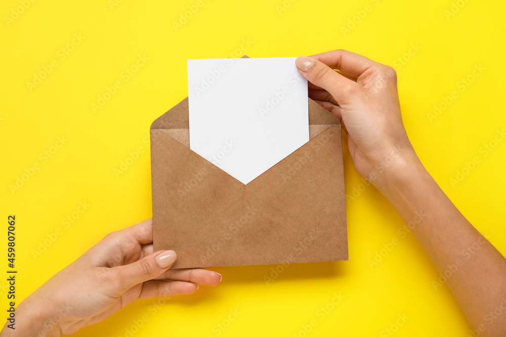 Female hands with envelope and blank card on color background
