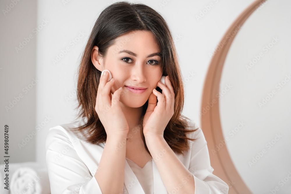 Beautiful young Asian woman with cotton wool in bathroom Beautiful young Asian woman with cotton wool in bathroom