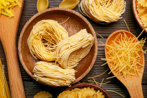 Different types of uncooked pasta on dark wooden background