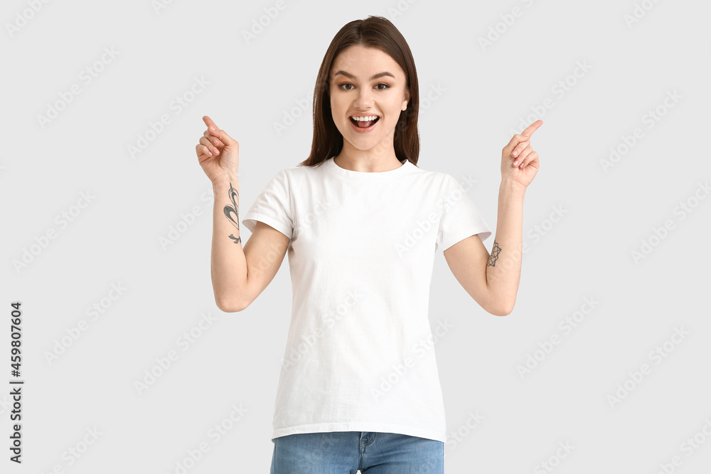 Young woman in modern t-shirt pointing at something on white background Young woman in modern t-shirt pointing at something on white background