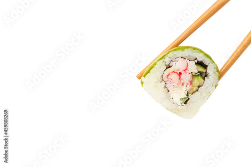 Chopsticks taking delicious sushi roll with avocado on white background