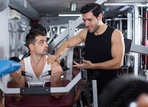 Portrait of sporty man during strength training with personal instructor in gym