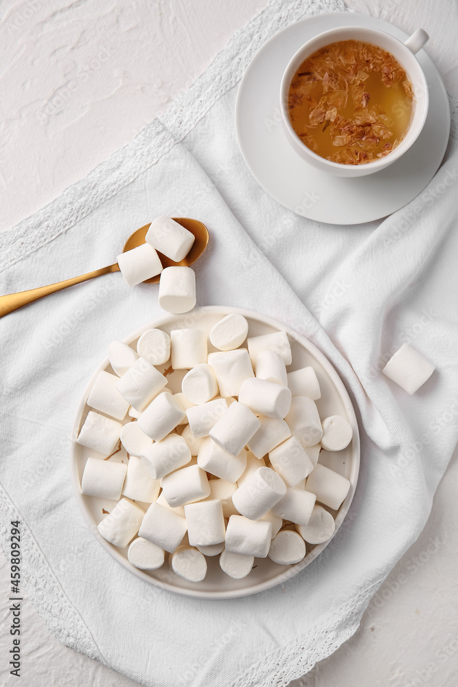 Plate with tasty marshmallows and cup of tea on light background Plate with tasty marshmallows and cup of tea on light background
