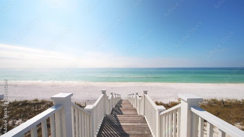 View on wooden boardwalk stairs steps railing leading to beach on sunny day in Seaside, Florida panhandle town village with ocean sea horizon in background View on wooden boardwalk stairs steps railing leading to beach on sunny day in Seaside, Florida panhandle town village with ocean sea horizon in background