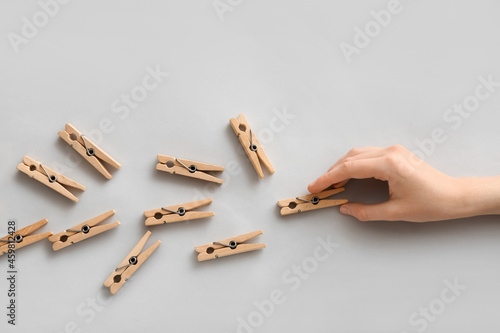 Female hand with clothespins on grey background