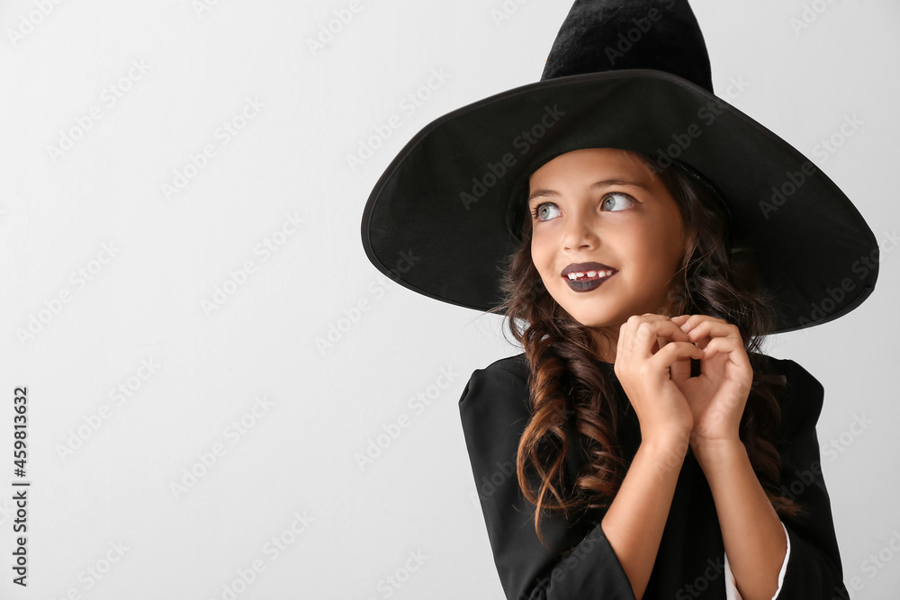 Cute little girl dressed as witch for Halloween on light background Cute little girl dressed as witch for Halloween on light background