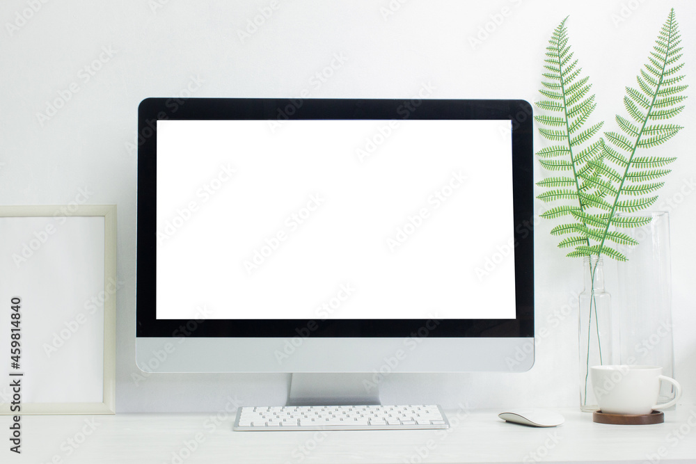 Fototapeta premium A mock up computer with green leaves on table.