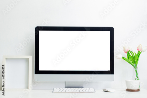 A mock up computer with blank screen and flowers on table. 