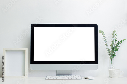 A mock up computer device with leaves and photo frame  on table.