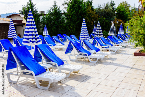 Empty chaise lounges and sun umbrellas near the swimming pool