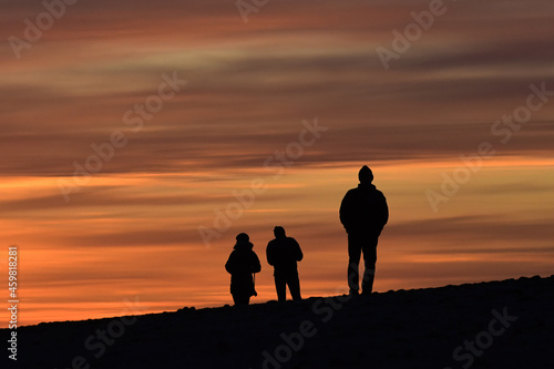 Silhouette of three people walking on the beach at sunset in Homer, Alaska.