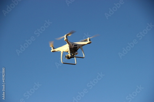 Quadcopter flying in the blue morning sky. Drone in the air.