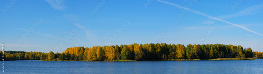 Autumn landscape. Panorama of the lake shore, clear sky and colorful forest. September or october in Russia.