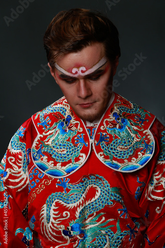 Chinese traditional warrior male costume at studio over grey background. Handsome man wearing national costume in Beijing, China