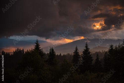 Amazing sunset among clouds over green mountains