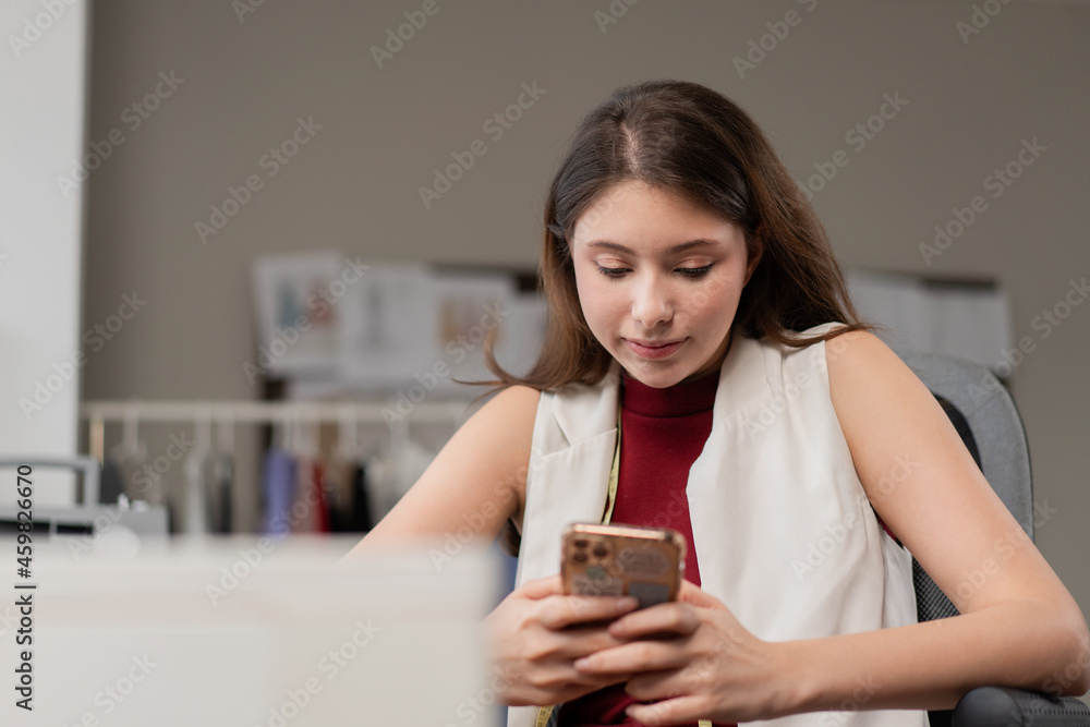 Young fashion designer woman check smartphone call to customer at office studio. Entrepreneur seller working on digital device. SME business online store. E-commerce shopping. social support service Young fashion designer woman check smartphone call to customer at office studio. Entrepreneur seller working on digital device. SME business online store. E-commerce shopping. social support service