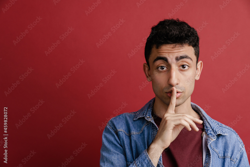 Young middle eastern man showing silence gesture at camera Young middle eastern man showing silence gesture at camera