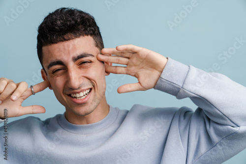 Young middle eastern man smiling and plugging his ears